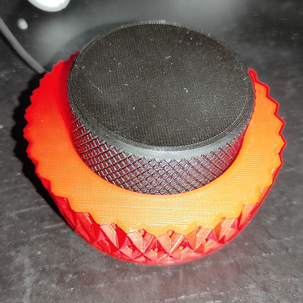 Photo of the volume knob showing the red base with a black knob with a rhombus texture pattern.